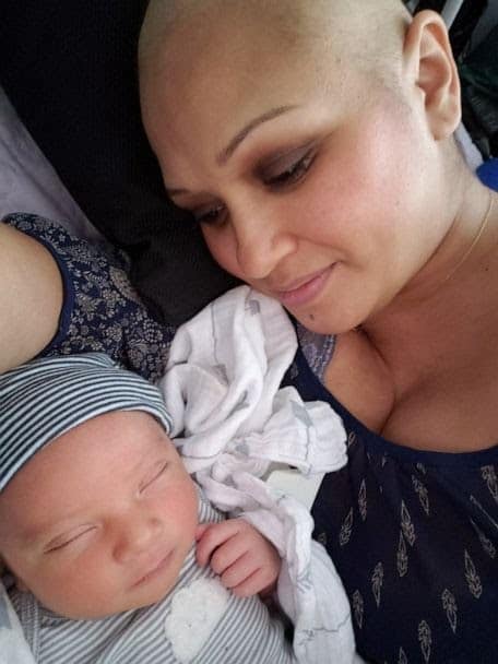 Proud mom gently kisses her miracle baby in powerful moment after surviving breast cancer during pregnancy.