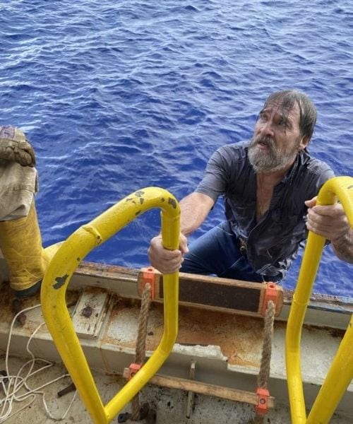 Stuart Bee climbing onto vessel after being rescued.