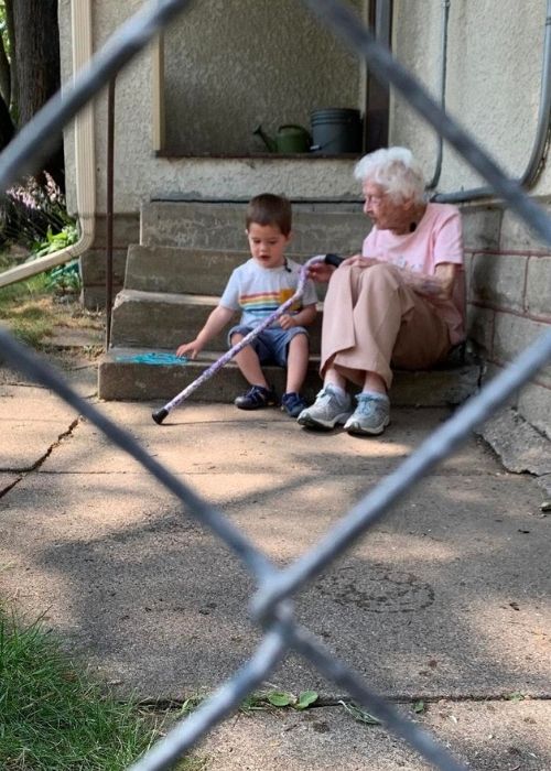 2-year-old Benjamin sitting with his new friend Mary on the steps in the backyard.